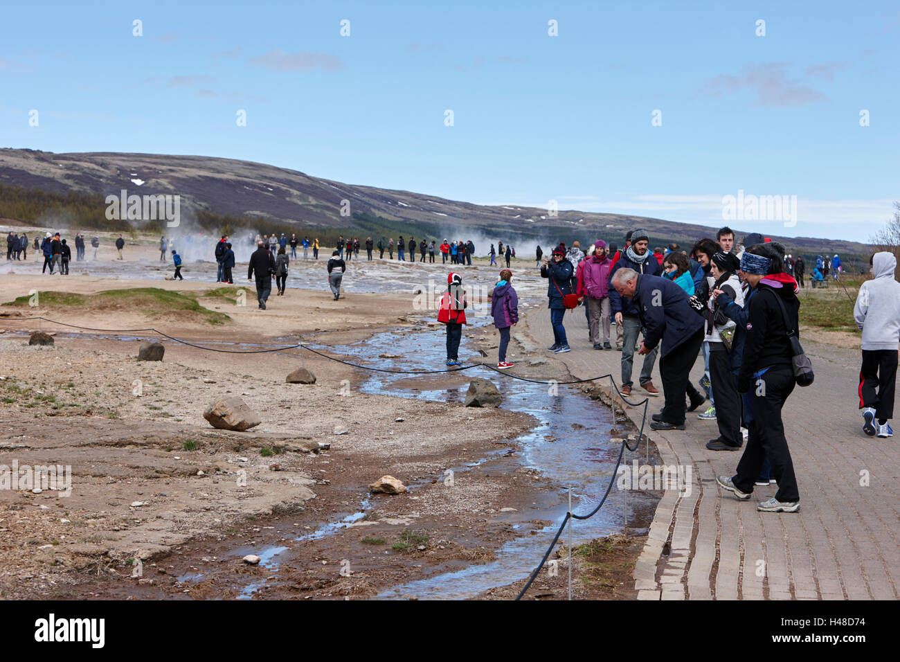 people walking through steam at Geysir site Iceland Stock Photo