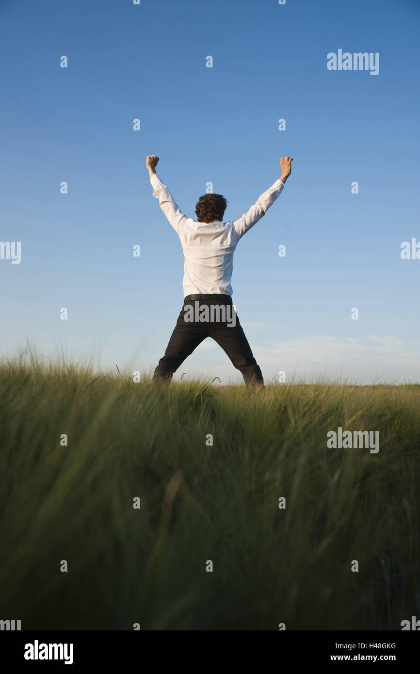 young manager stands in a field, joy, cheering, back view, Stock Photo