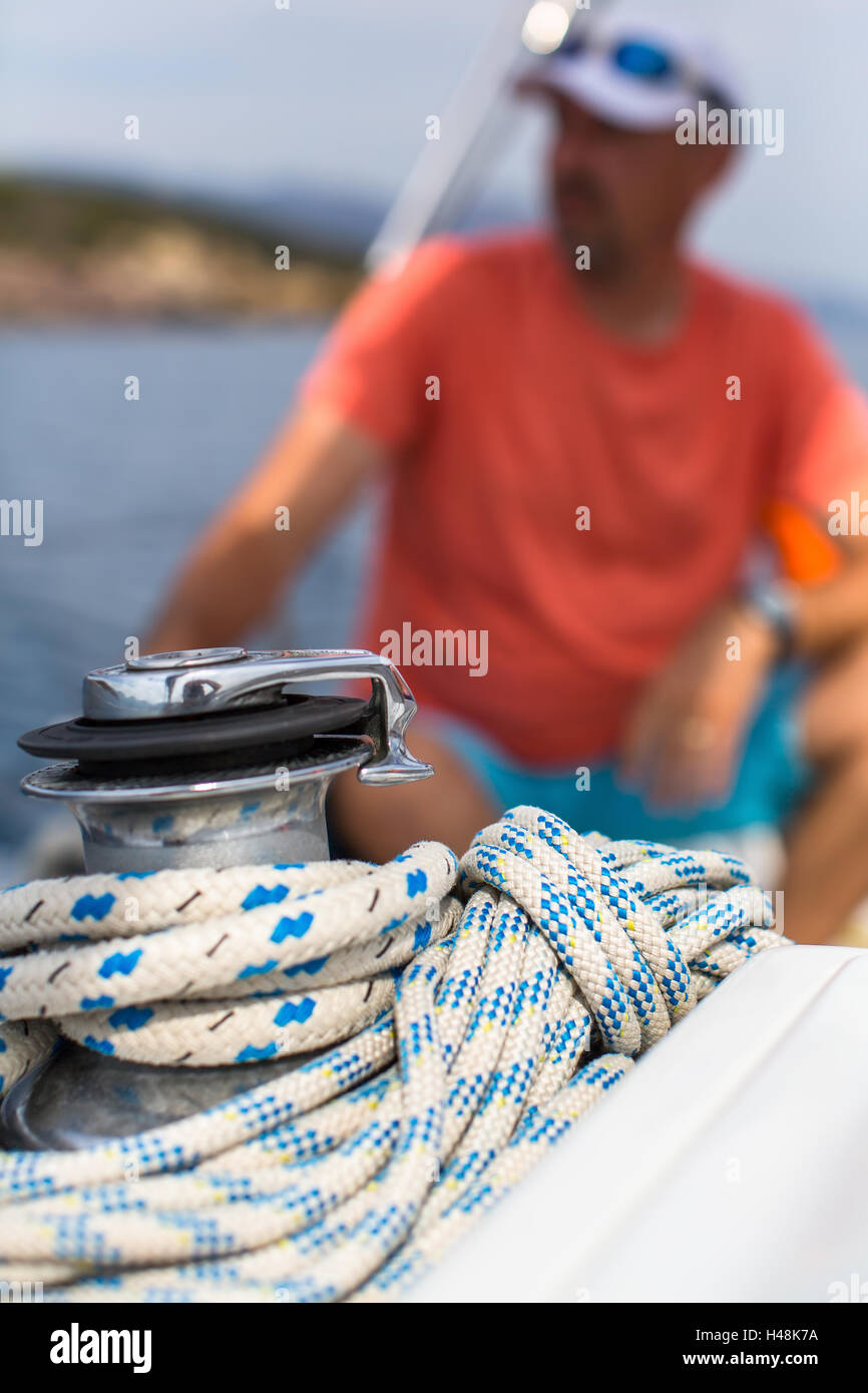 Rope on the yacht, a sailor is blurred in the background. Stock Photo