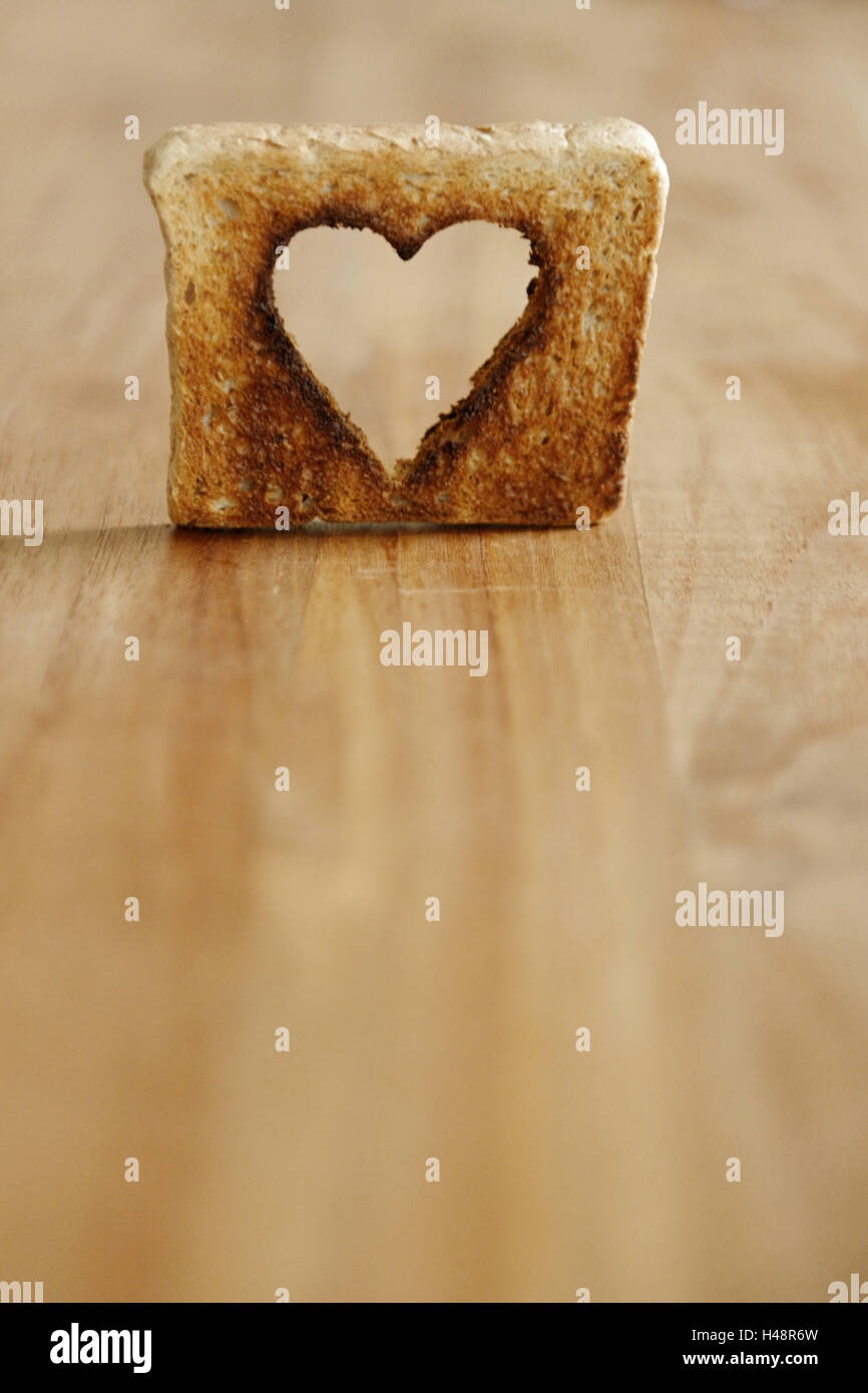 Toast with punched out heart on wooden table, studio, Stock Photo