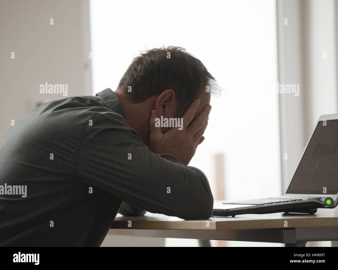 Man sits desperately before his laptop, Stock Photo