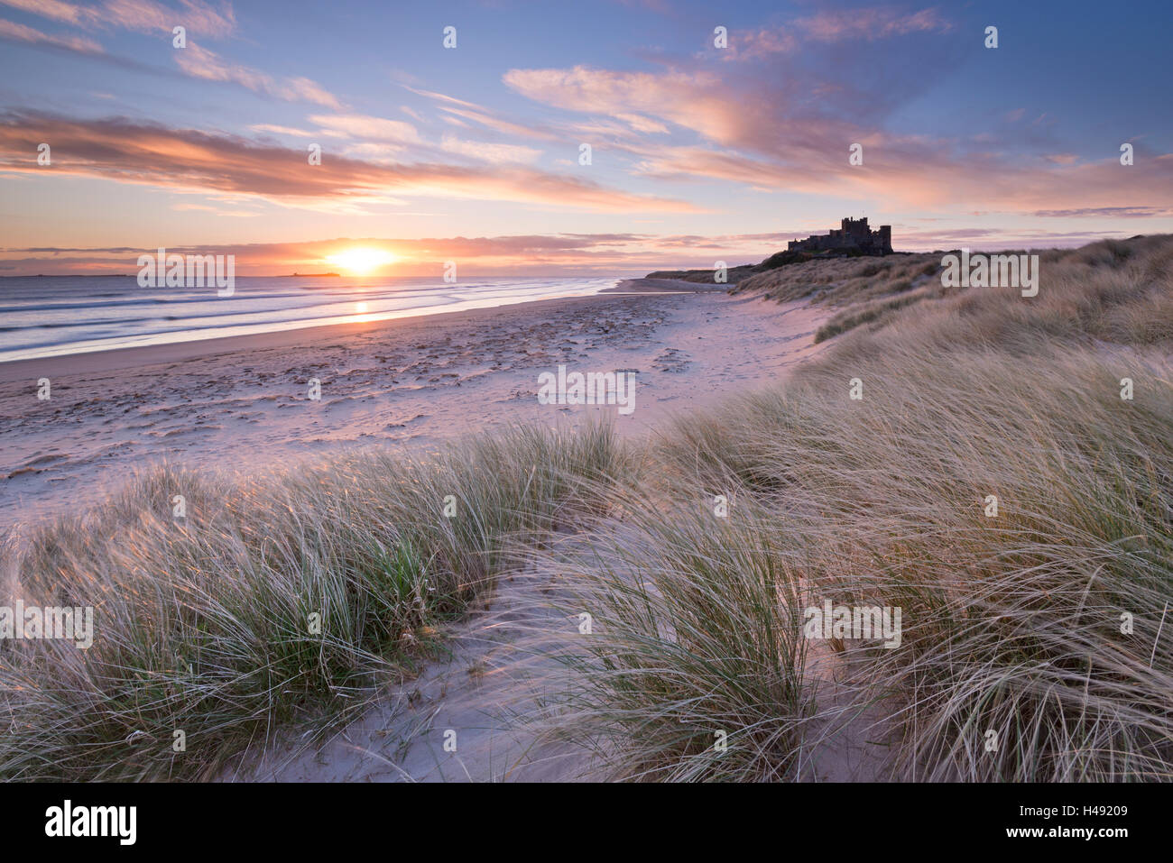 Sunrise over Bamburgh Beach and Castle from the sand dunes, Northumberland, England. Spring (March) 2014. Stock Photo