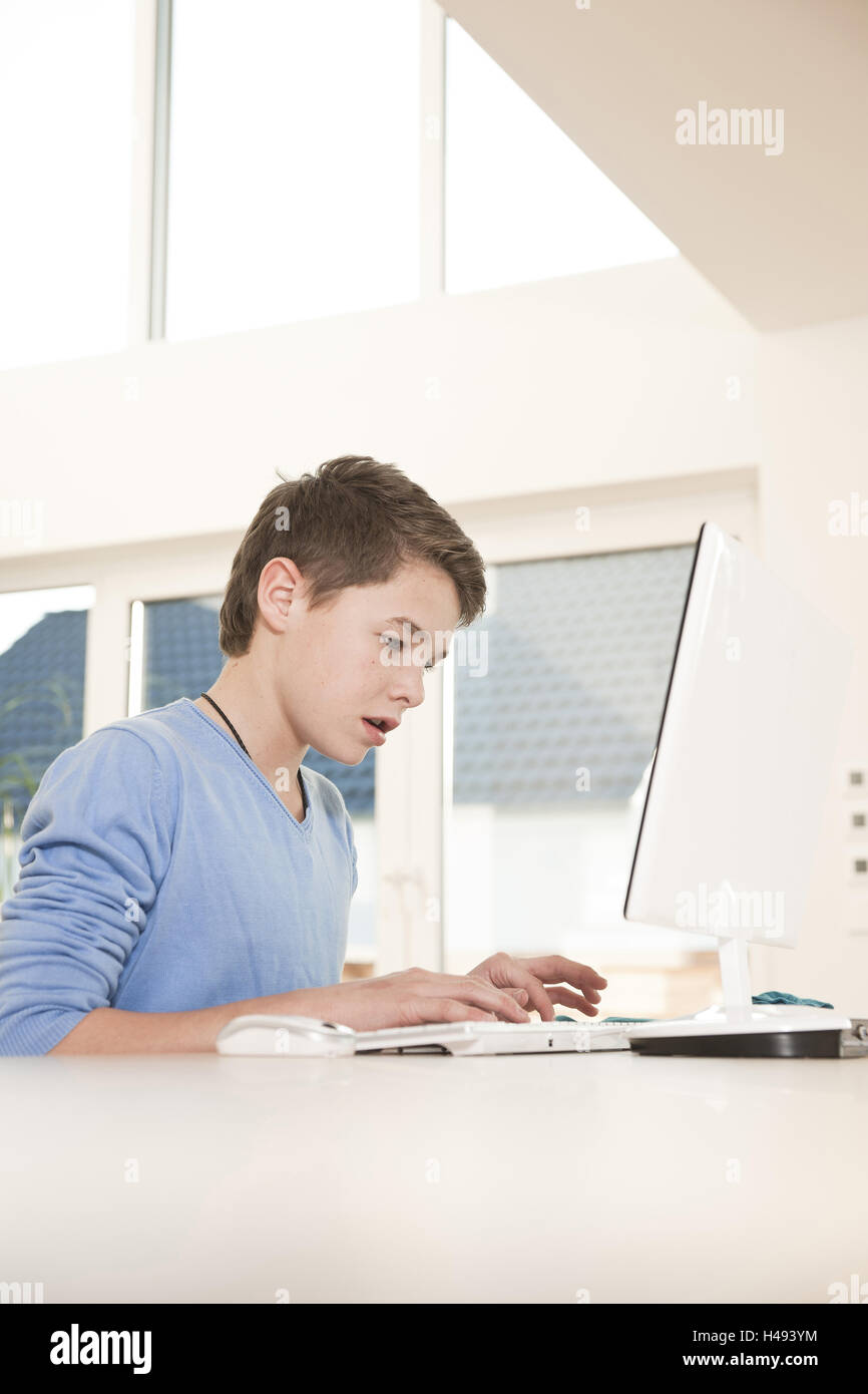 Boy works intently on the computer, Stock Photo