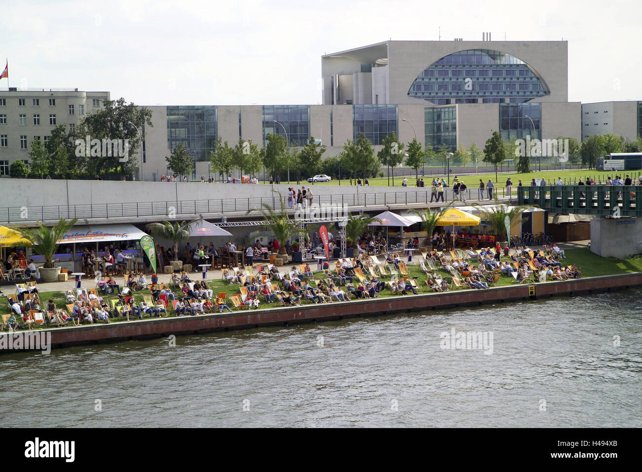 Germany, Berlin, Ludwig's Erhard shore, promenade, 'Capital-Beach', sunbathing area, guests, Spree shores, chancellery, summer, Berlin zoo, event gastronomy, gastronomy, cafe, bar, Capital Beach bar, street bar, street cafe, street restaurant, palms, way, footpath, riverside, meadow, deck chairs, people, passers-by, tourists, sit, sun themselves, leisure time, recreation, amusement, Office the Federal Chancellor, tourism, town view, Stock Photo