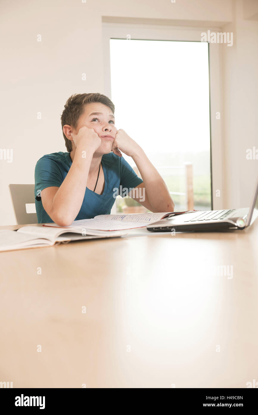 Boy sits frustrated before his school works, Stock Photo