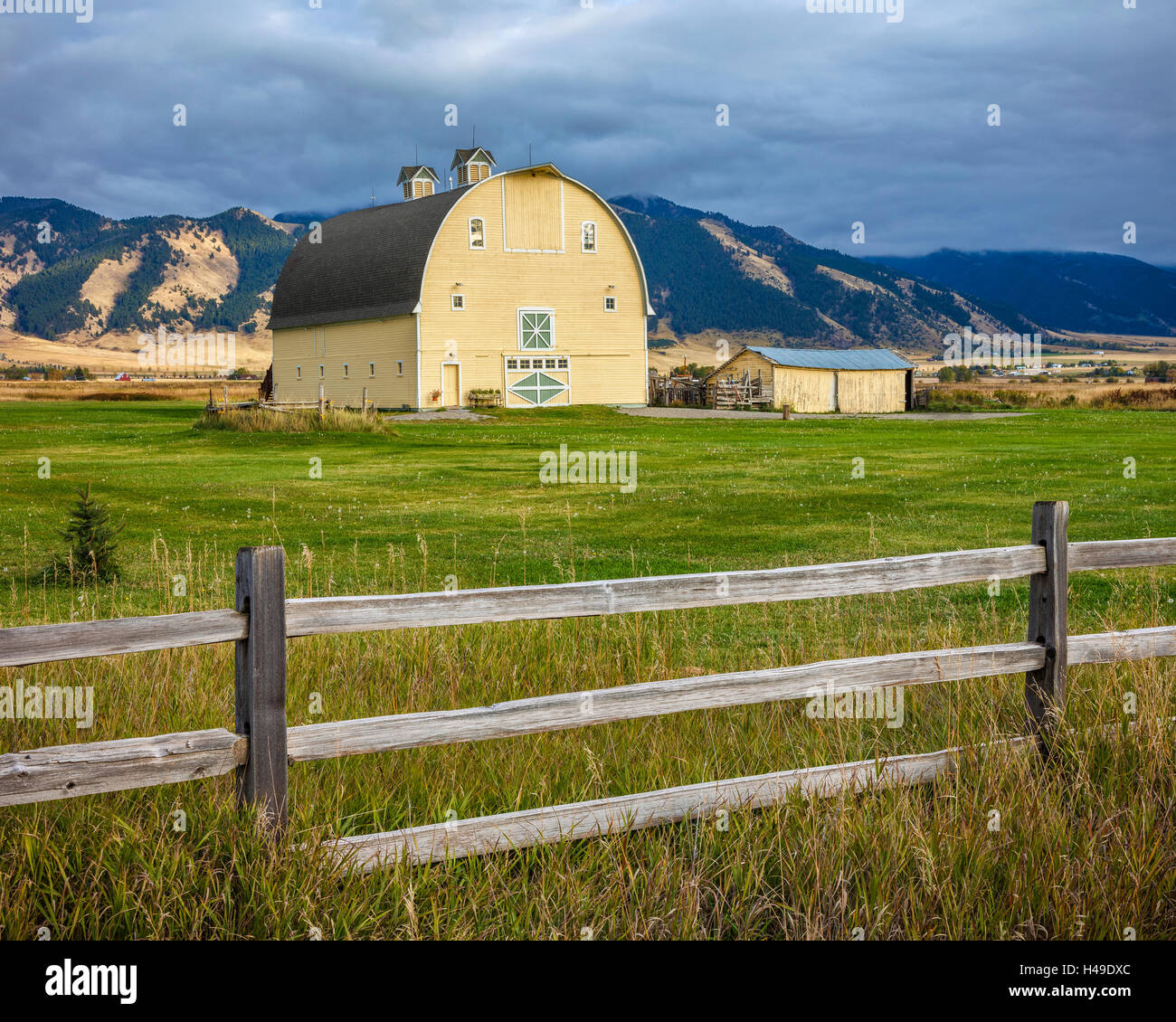 Gallatin County, MT: Yellow barn and wood fence line under the Bridger Range Stock Photo