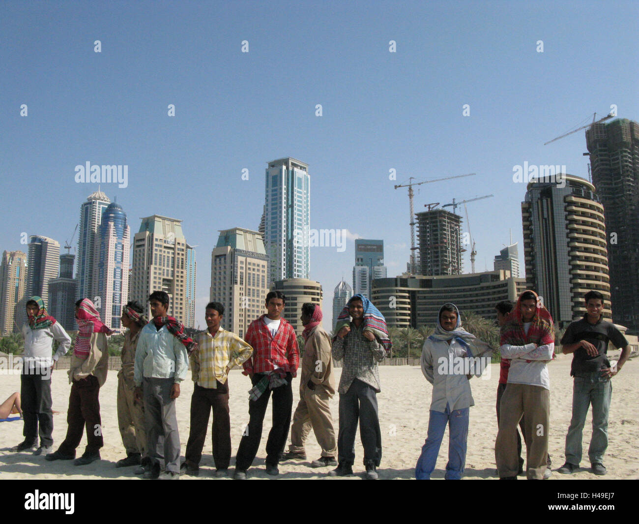 United Arab Emirates, Dubai, Jumeirah Beach, high rises, workers, group, stand, town, part town, hotels, hotel buildings, flatlets, high rises, architecture, skyline, tourism, destination, beach, person, men, outside, group picture, cranes, Stock Photo