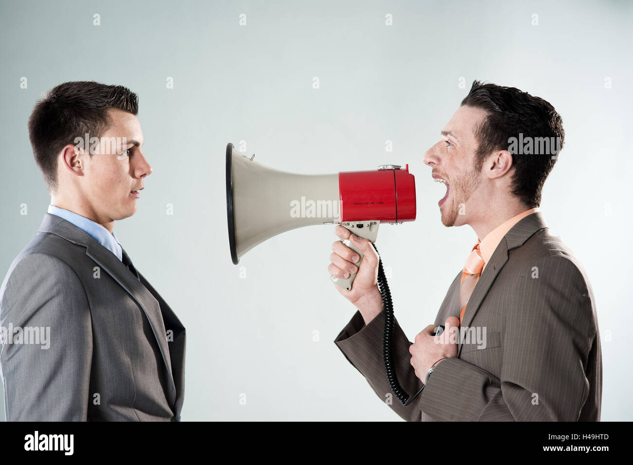 Young entrepreneur shouts at his colleague with the megaphone, Stock Photo