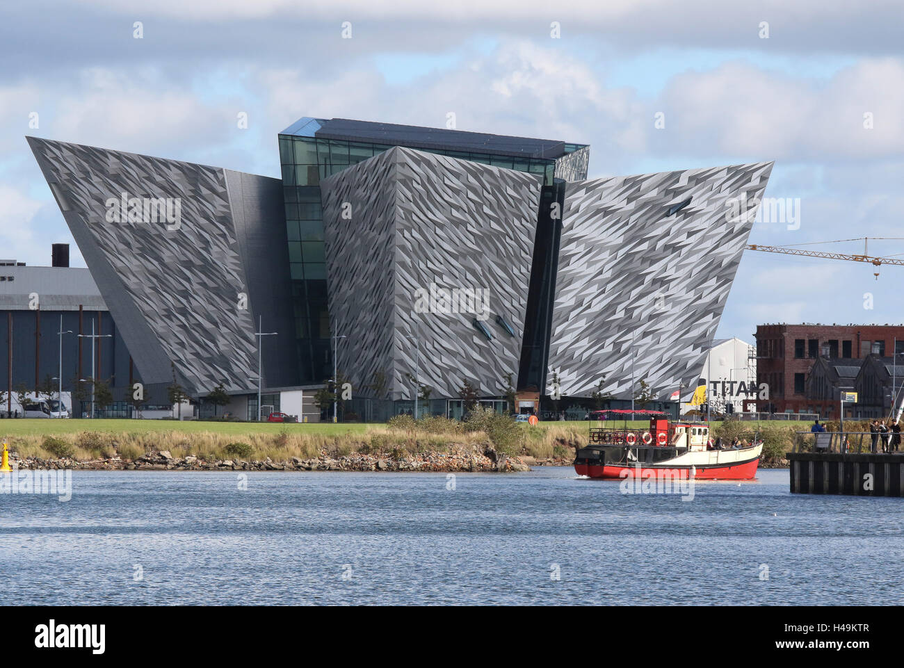The Titanic Building  in Belfast's Titanic Quarter.In the foreground is the 'Mona', a boat used for Titanic Boat Tours. Stock Photo
