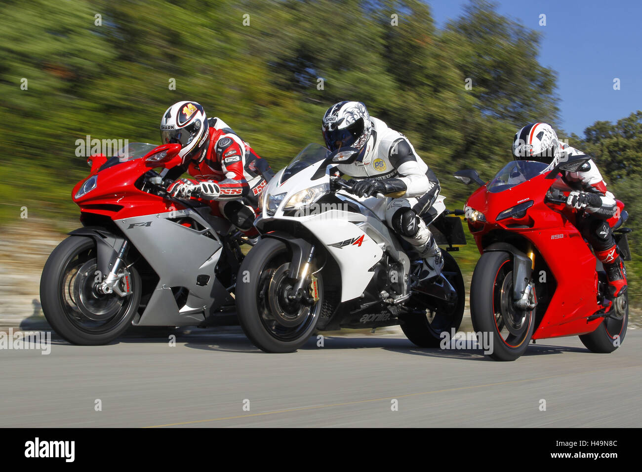 three motorcyclists, off-centre side by side, Italian 1000th, country road, side view, Stock Photo