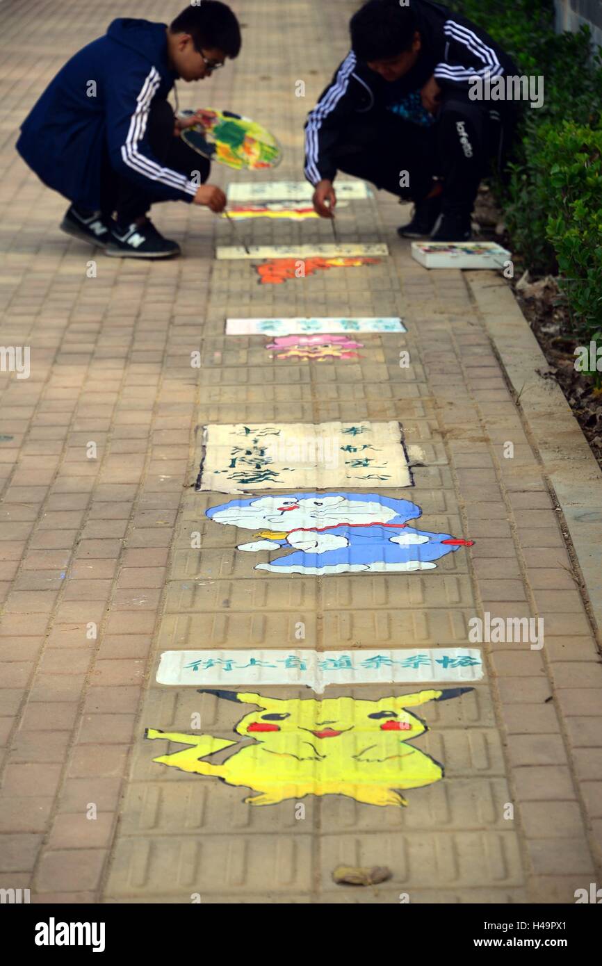 Liaocheng, Liaocheng, China. 14th Oct, 2016. Liaocheng, CHINA-October 14 2016: (EDITORIAL USE ONLY. CHINA OUT) Students from Fine Arts College of Liaocheng University draw creative cartoon characters including Garfield Cat and Doraemon on blind sidewalk in Liaocheng, east ChinaÂ¡Â¯s Shandong Province, on October 14th, 2016, marking the upcoming White Cane Safety Day and appealing the public to care for visually impaired people. The White Cane Safety Day, celebrated on October 15 of each year since 1964, is set aside to celebrate the achievements of people who are blind or visually impaired an Stock Photo
