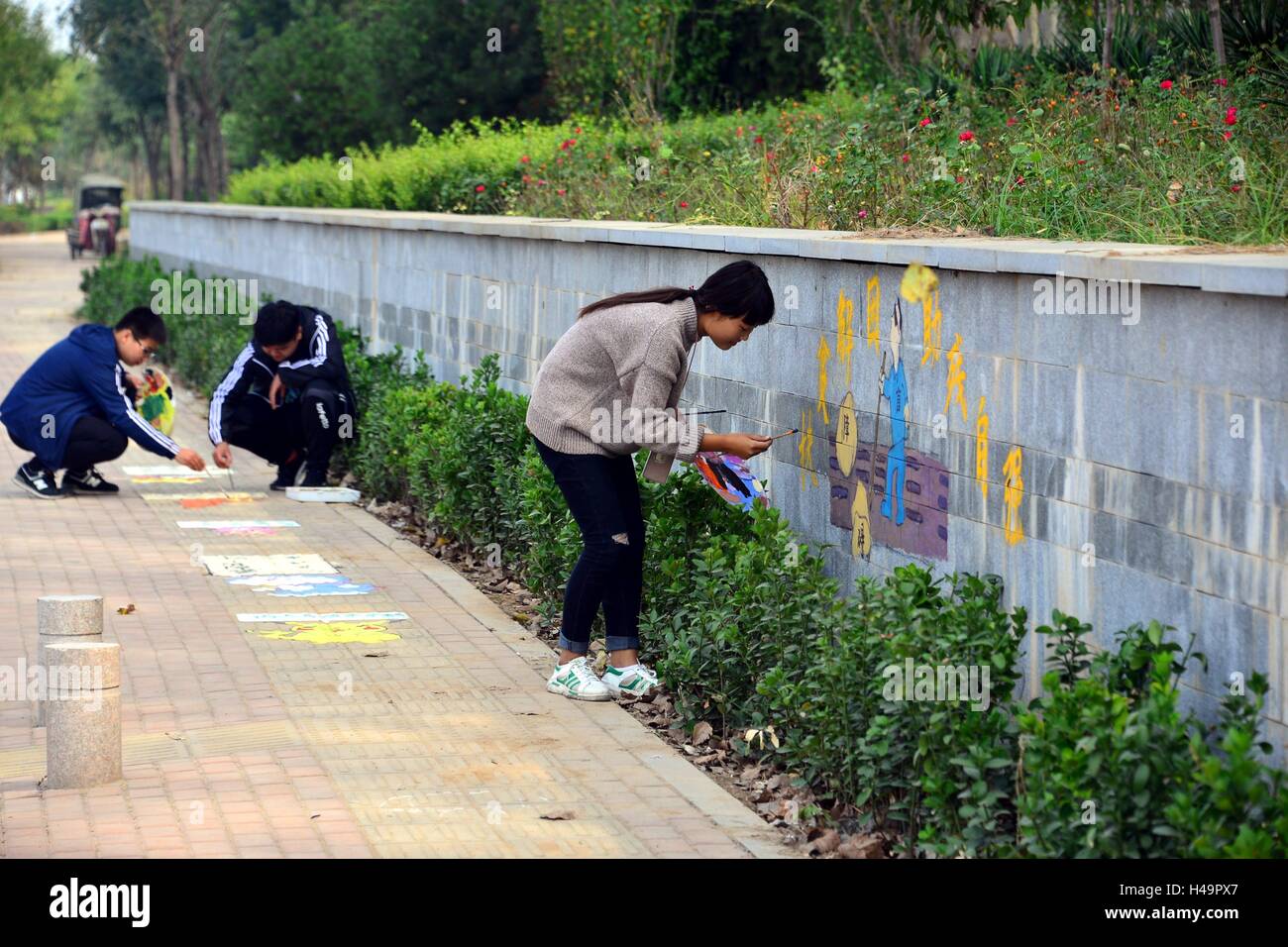 Liaocheng, Liaocheng, China. 14th Oct, 2016. Liaocheng, CHINA-October 14 2016: (EDITORIAL USE ONLY. CHINA OUT) Students from Fine Arts College of Liaocheng University draw creative cartoon characters including Garfield Cat and Doraemon on blind sidewalk in Liaocheng, east ChinaÂ¡Â¯s Shandong Province, on October 14th, 2016, marking the upcoming White Cane Safety Day and appealing the public to care for visually impaired people. The White Cane Safety Day, celebrated on October 15 of each year since 1964, is set aside to celebrate the achievements of people who are blind or visually impaired an Stock Photo