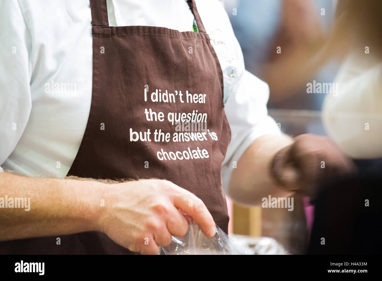 Exhibitor wears a brown apron with a good quote. The Chocolate Show takes place at Olympia London, UK  from 14th-16th October 2016, as the grand finale of Chocolate Week. © Laura De Meo/Alamy Live News Credit:  Laura De Meo/Alamy Live News Stock Photo
