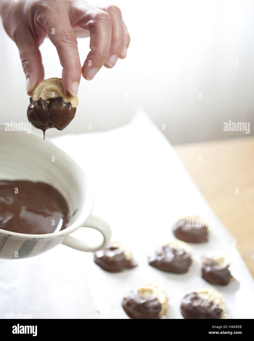Woman, baking cookies, dipping in chocolate, close-up, Stock Photo