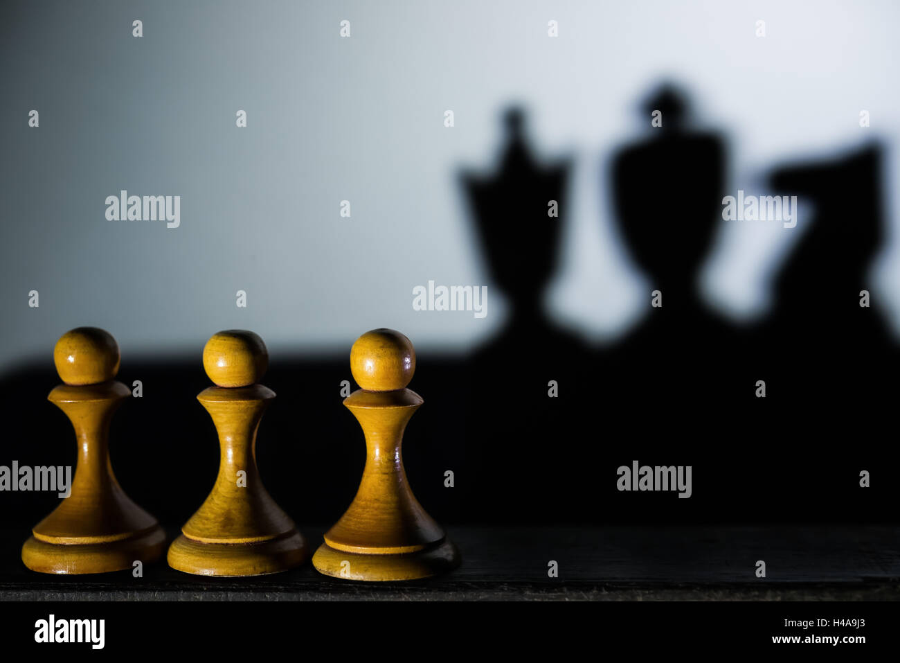 three chess pawn casting Queen King and Knight shadow in dark concept of strength and aspirations Stock Photo