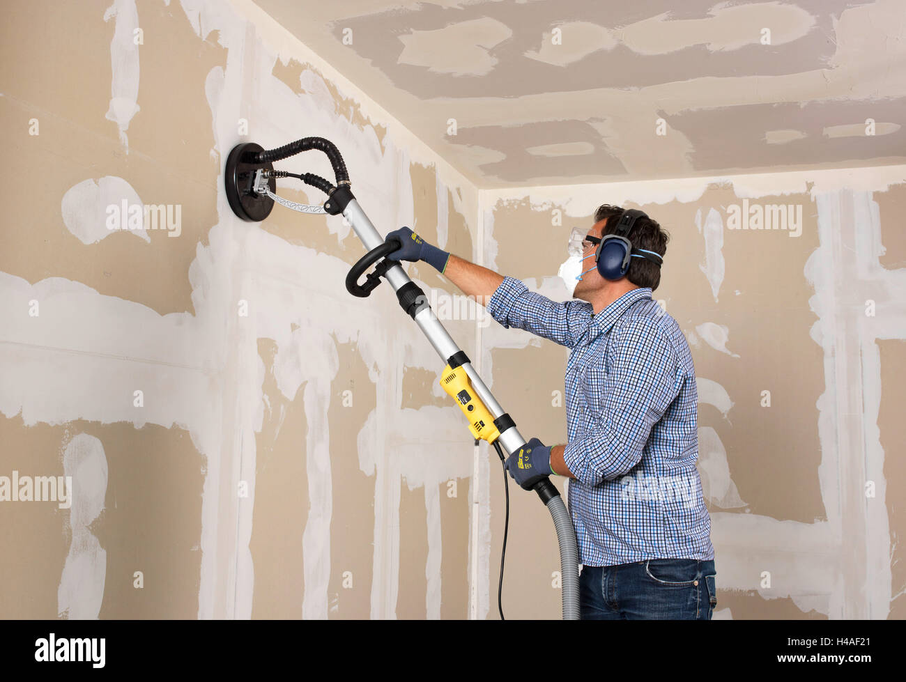 Man, drywall installation grinder, shell construction, building site Stock Photo