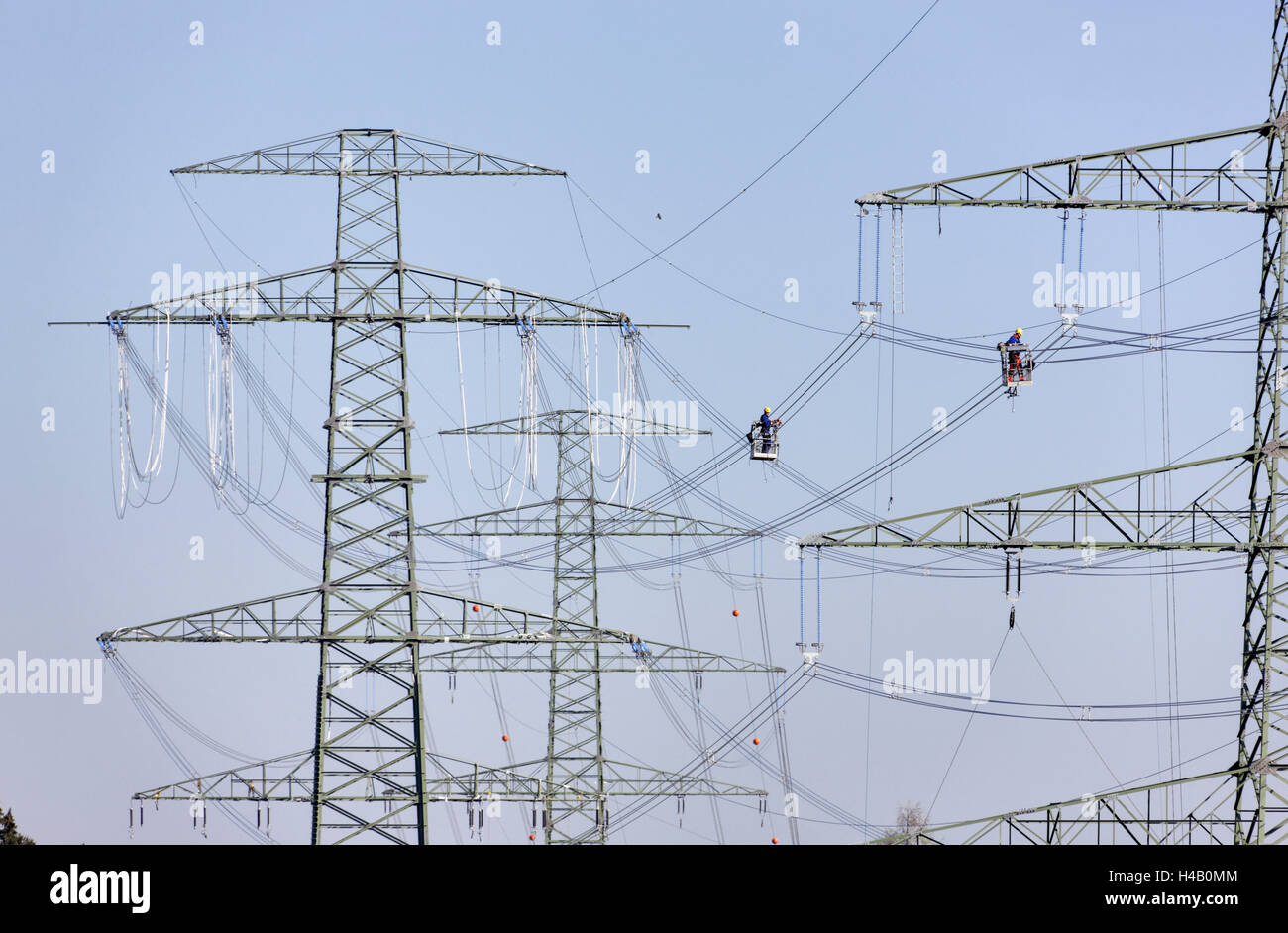 High-voltage poles, wires, two men working on power line installation, gondolas, wire installation, Thuringian Forest Stock Photo