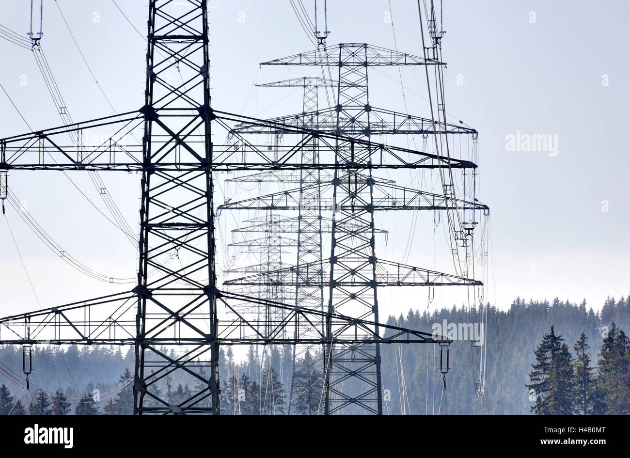 High-voltage poles, forest, silhouettes, back light, Thuringian Forest Stock Photo