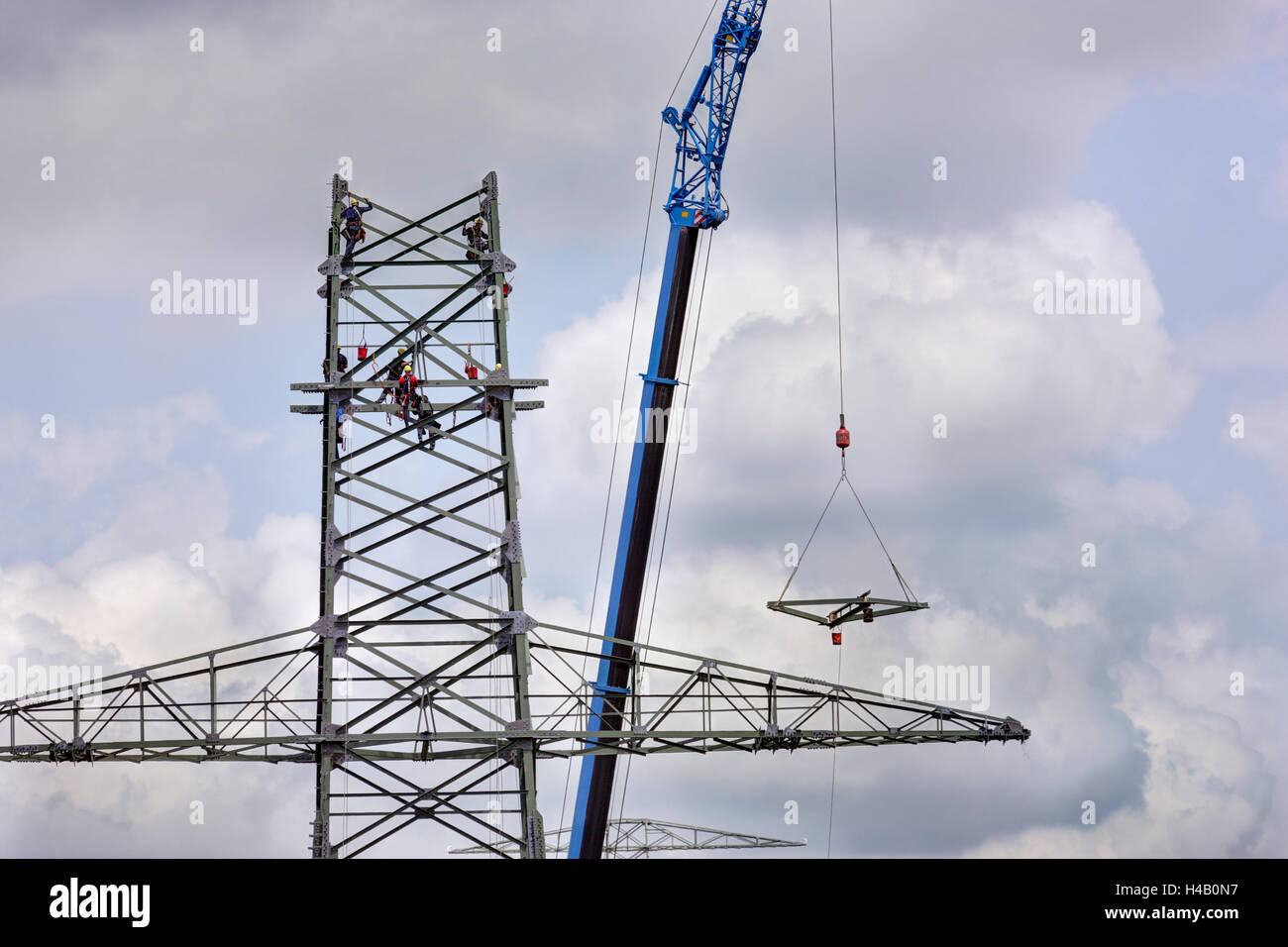 Assembling of the pylon, men working in the high-voltage power pylon, crane raising part of the pylon, Thuringian Forest Stock Photo