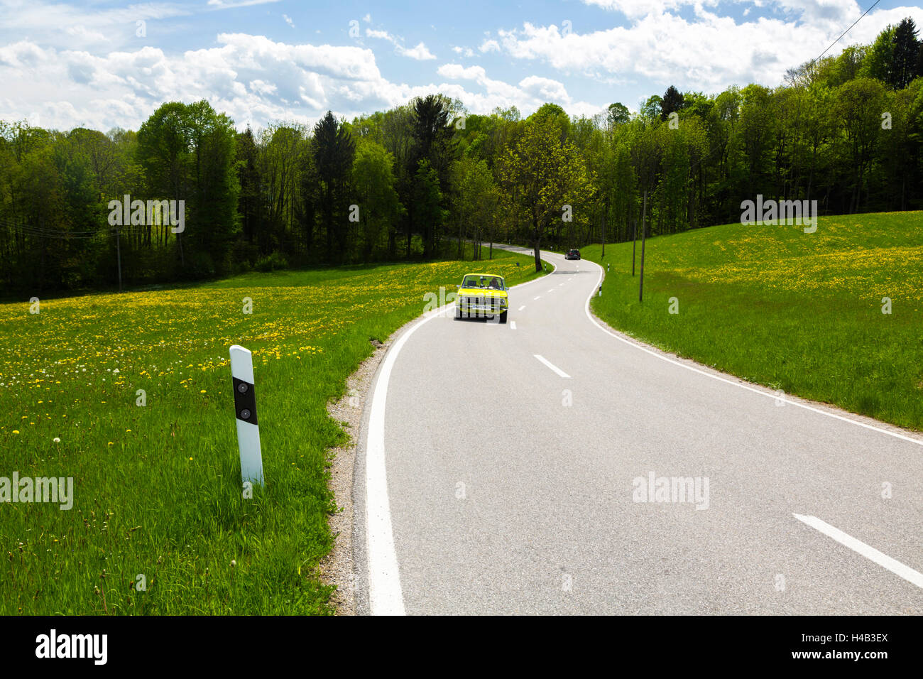 Germany, Bavaria, green car driving on country road in spring Stock Photo