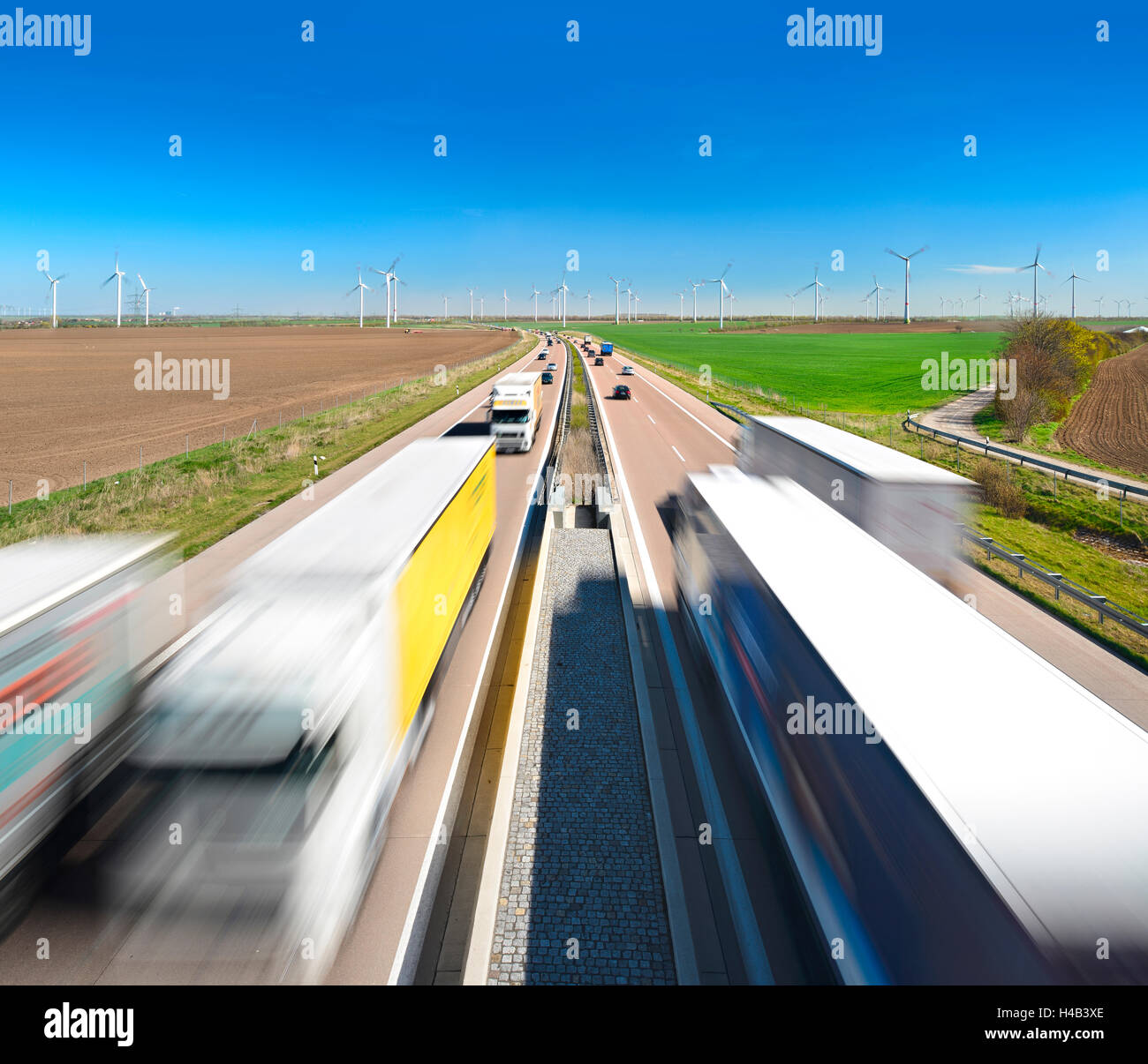 Germany, Saxony-Anhalt, Autobahn A38 near Querfurt, truck and car in motion blur, wind turbines at the horizon Stock Photo