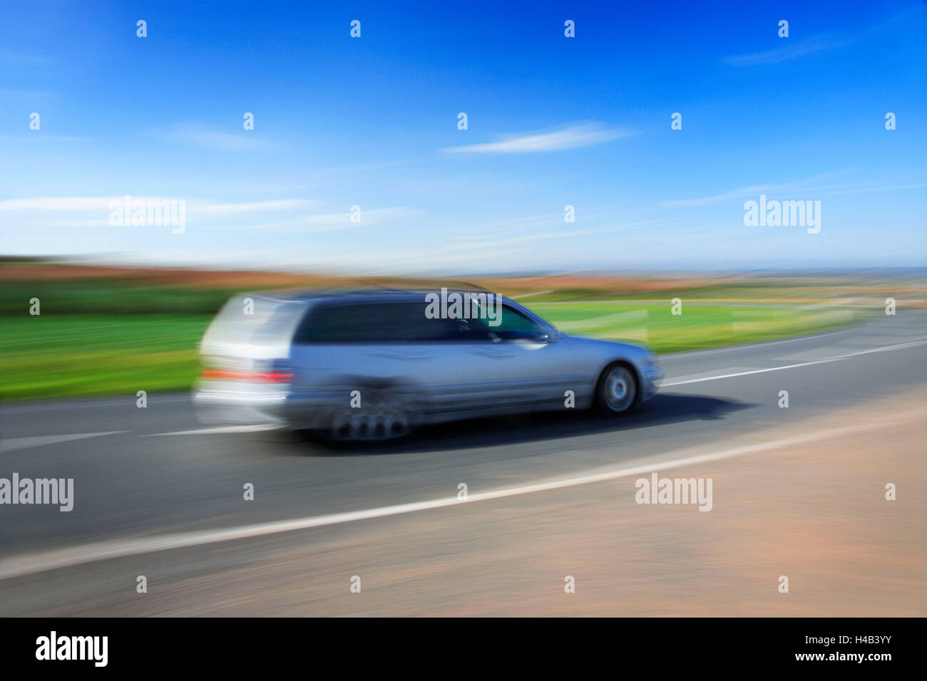 Silver estate car driving on country road under blue sky, motion blur Stock Photo