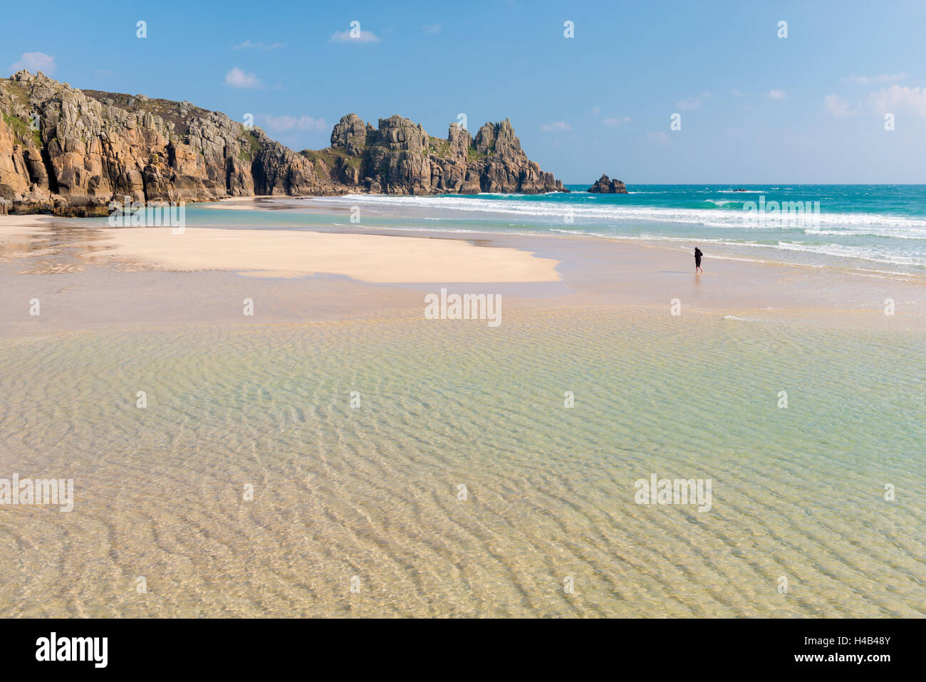 Woman walking alone on Pednvounder Beach at low tide, Porthcurno, Cornwall, England. Spring (April) 2013. Stock Photo