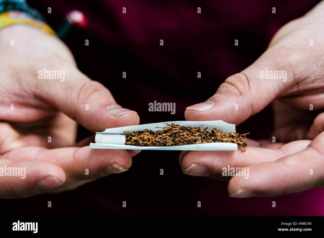 Hands rolling a cigarette with tobacco and filter, smoking Stock Photo