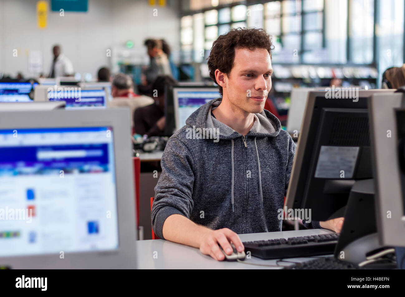 Smiling student using a computer in a library to perform some researches for high school Stock Photo