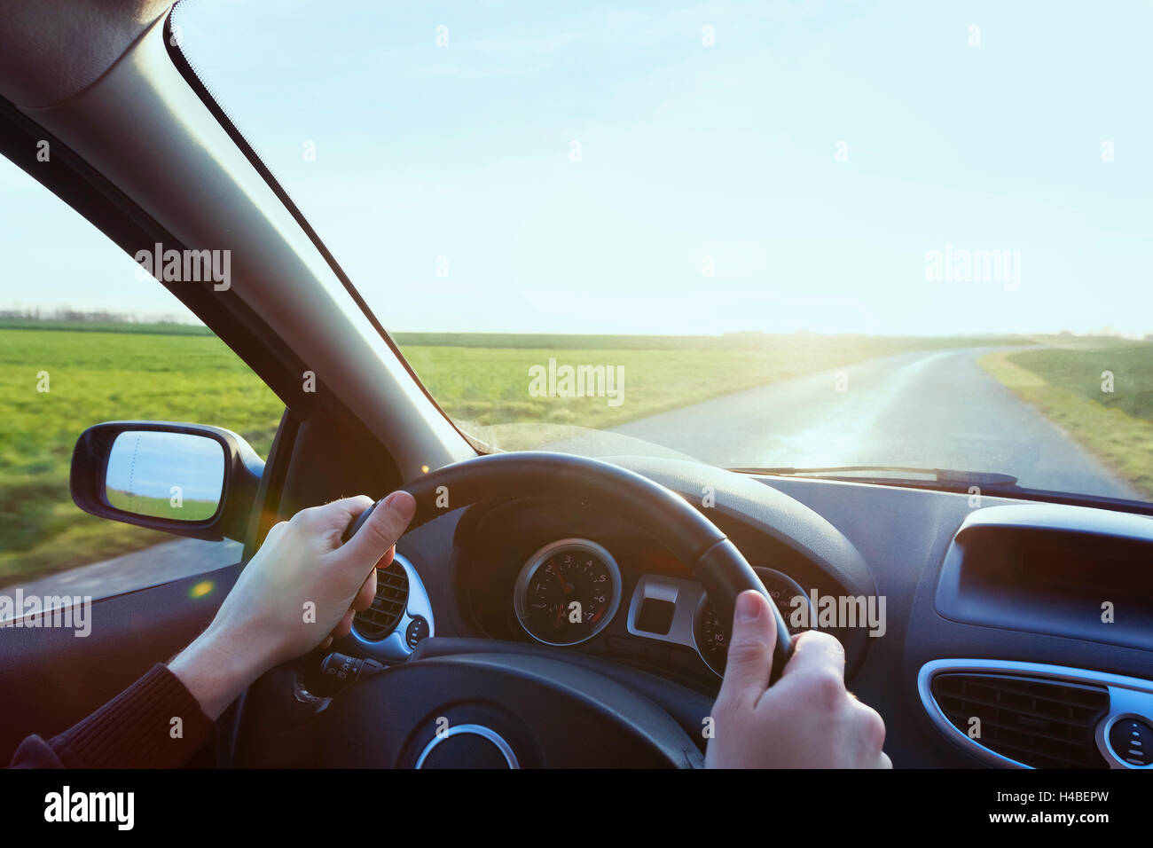 Person driving car with blue sky and green grass Stock Photo