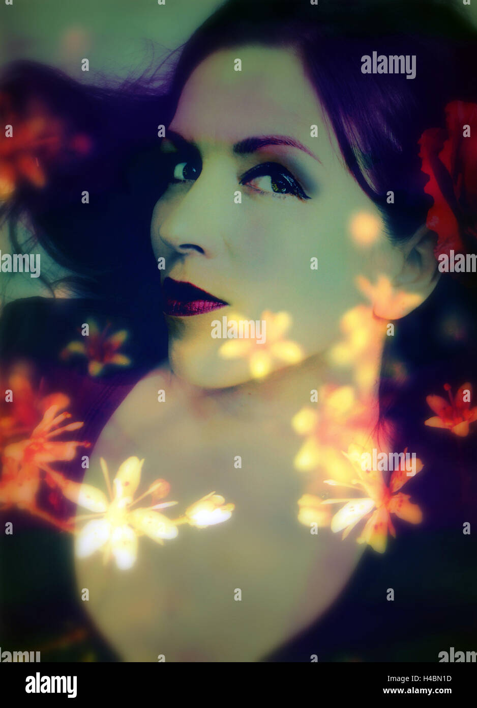 a moody evening portrait of a woman with bright flower appearence Stock Photo