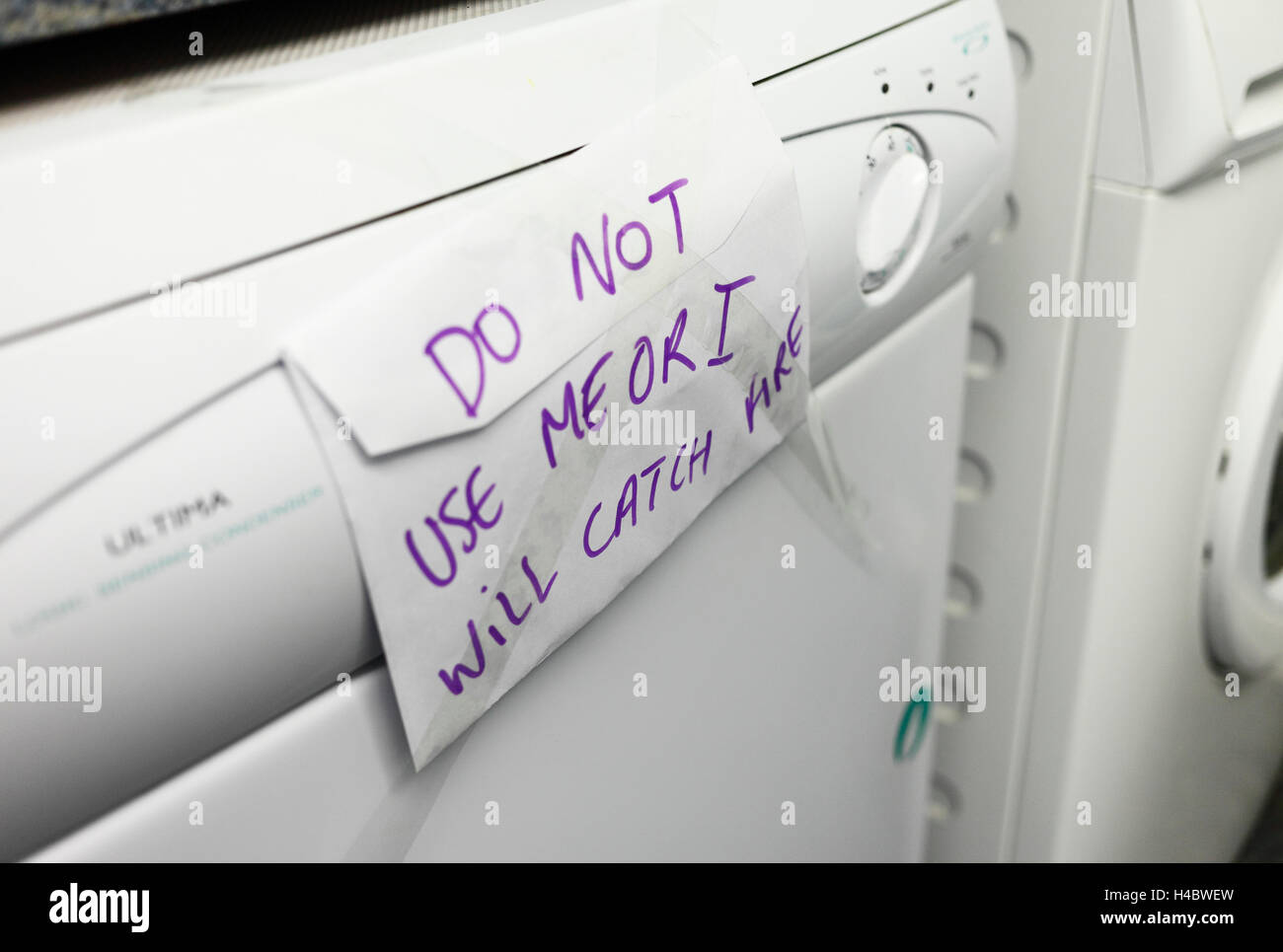 Faulty tumble drier with a warning sign not to use. Stock Photo