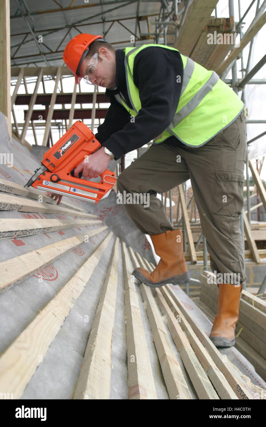 A roofer uses a gaspowered nail gun to fix timber battens to the roof