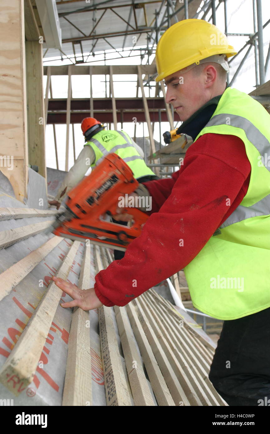 A roofer uses a gaspowered nail gun to fix timber battens to the roof