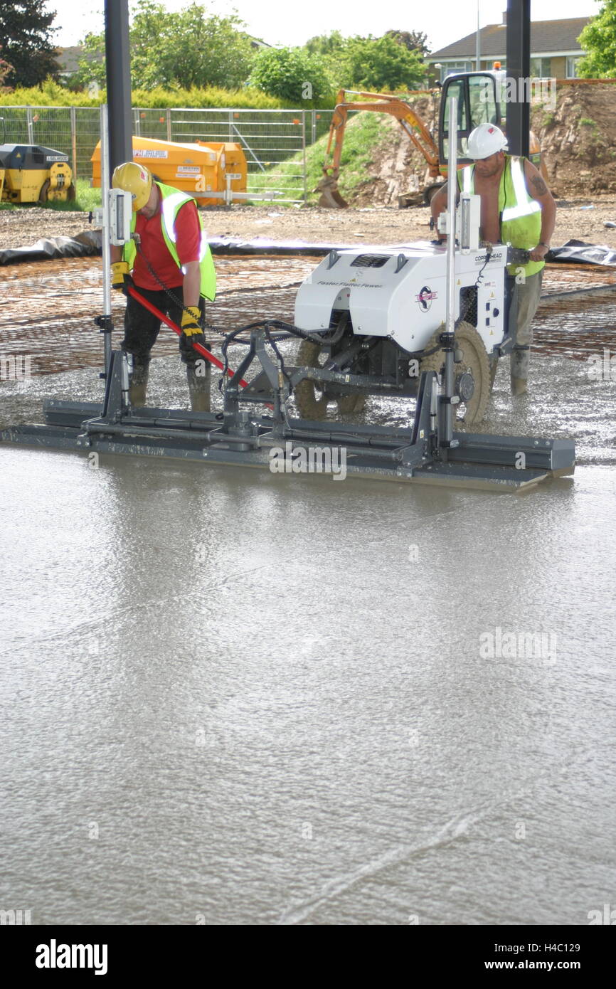 Workmen use a computer controlled, laser leveled screeding machine to ...