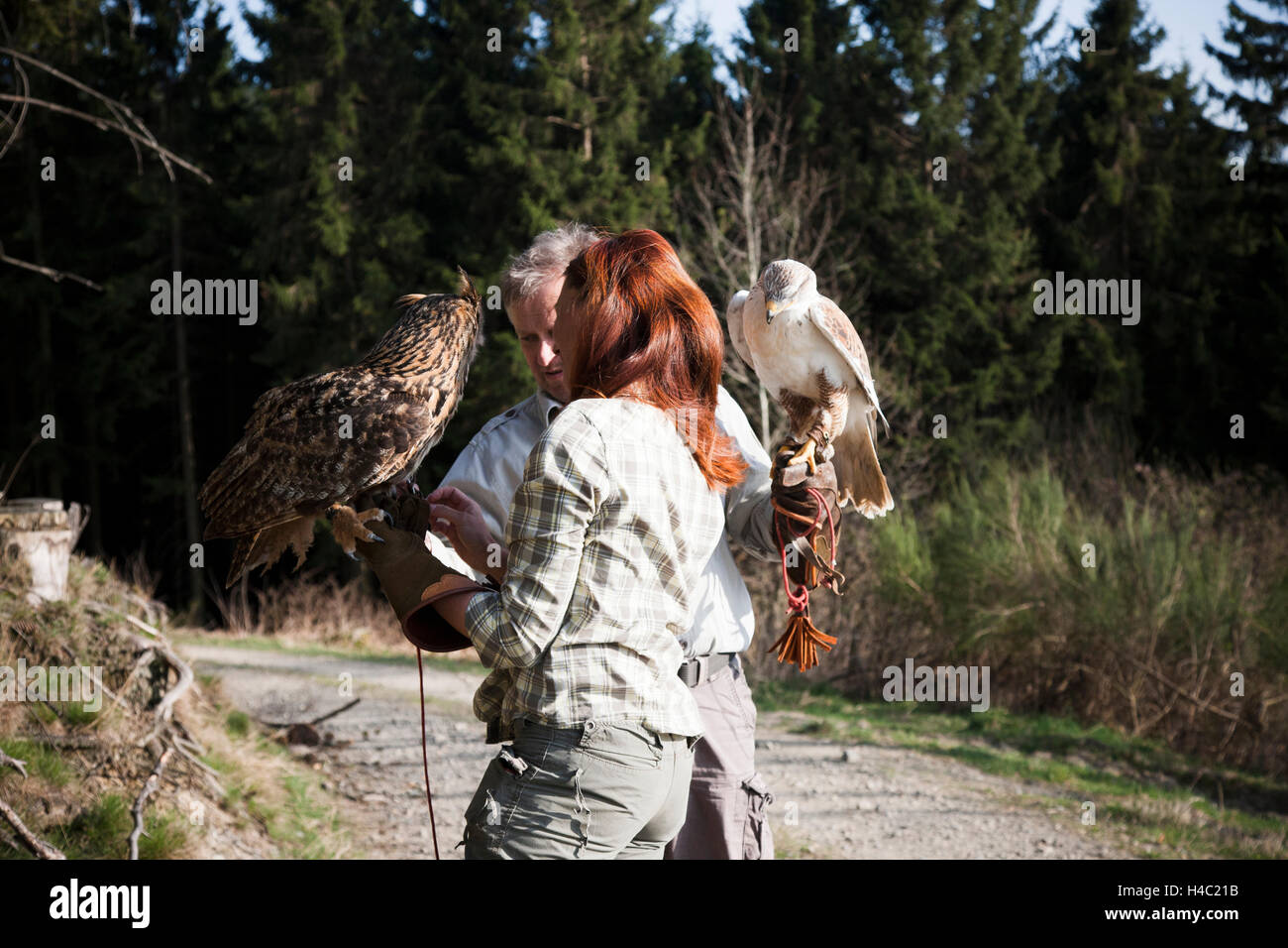 Falconer and female falconers holding eagle owl and ferruginous hawk on the hands Stock Photo