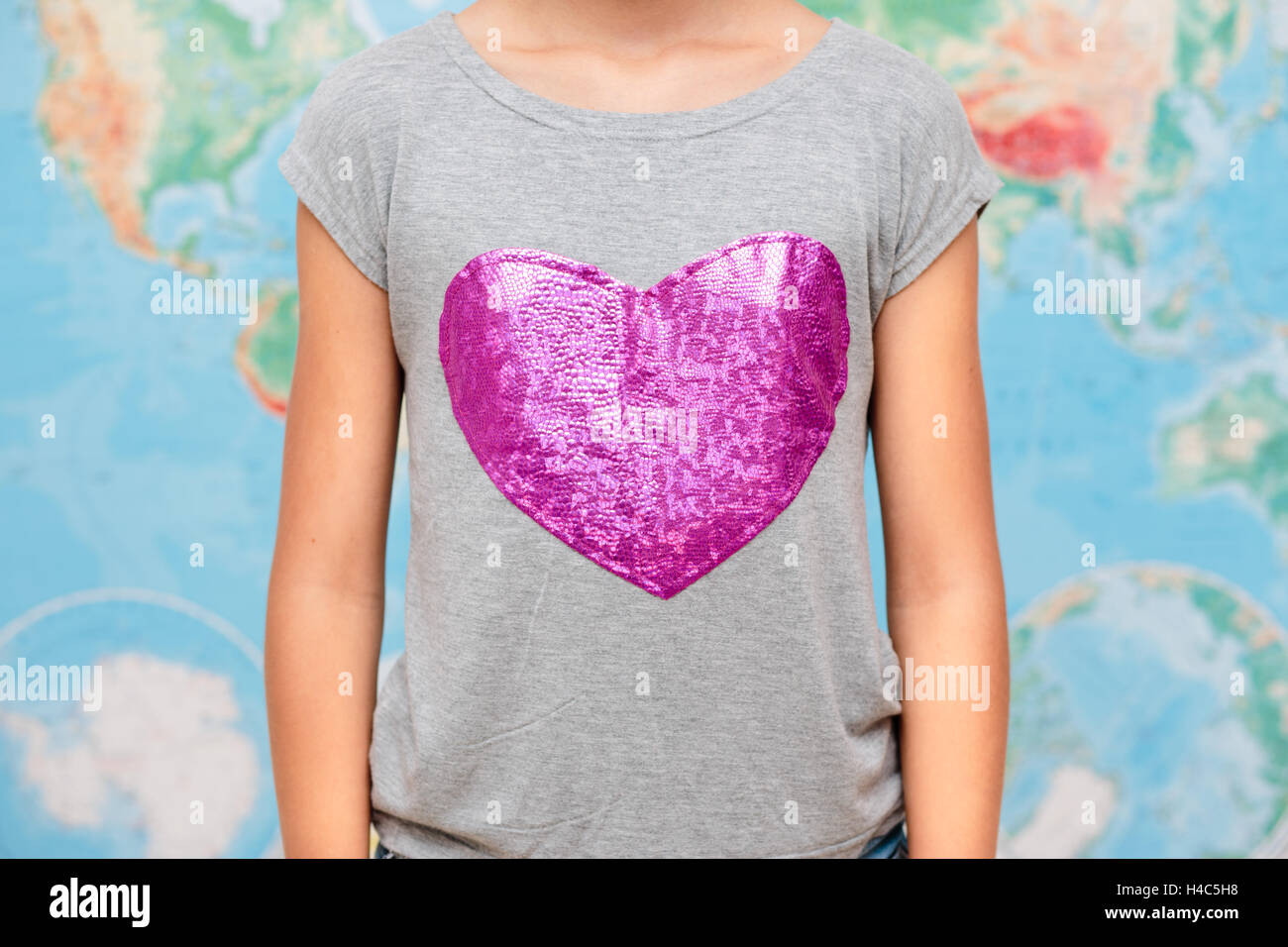 Girl with heart shape on t-shirt with map of world in the background Stock Photo