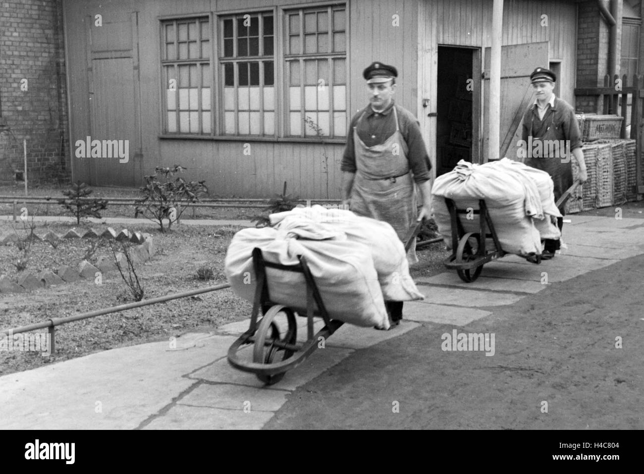 Mitarbeiter der Mitropa beim Verladen von Wäschesäcken, Deutschland 1930er Jahre. Mitropa staff members loading sacks of laundry, Germany 1930s Stock Photo