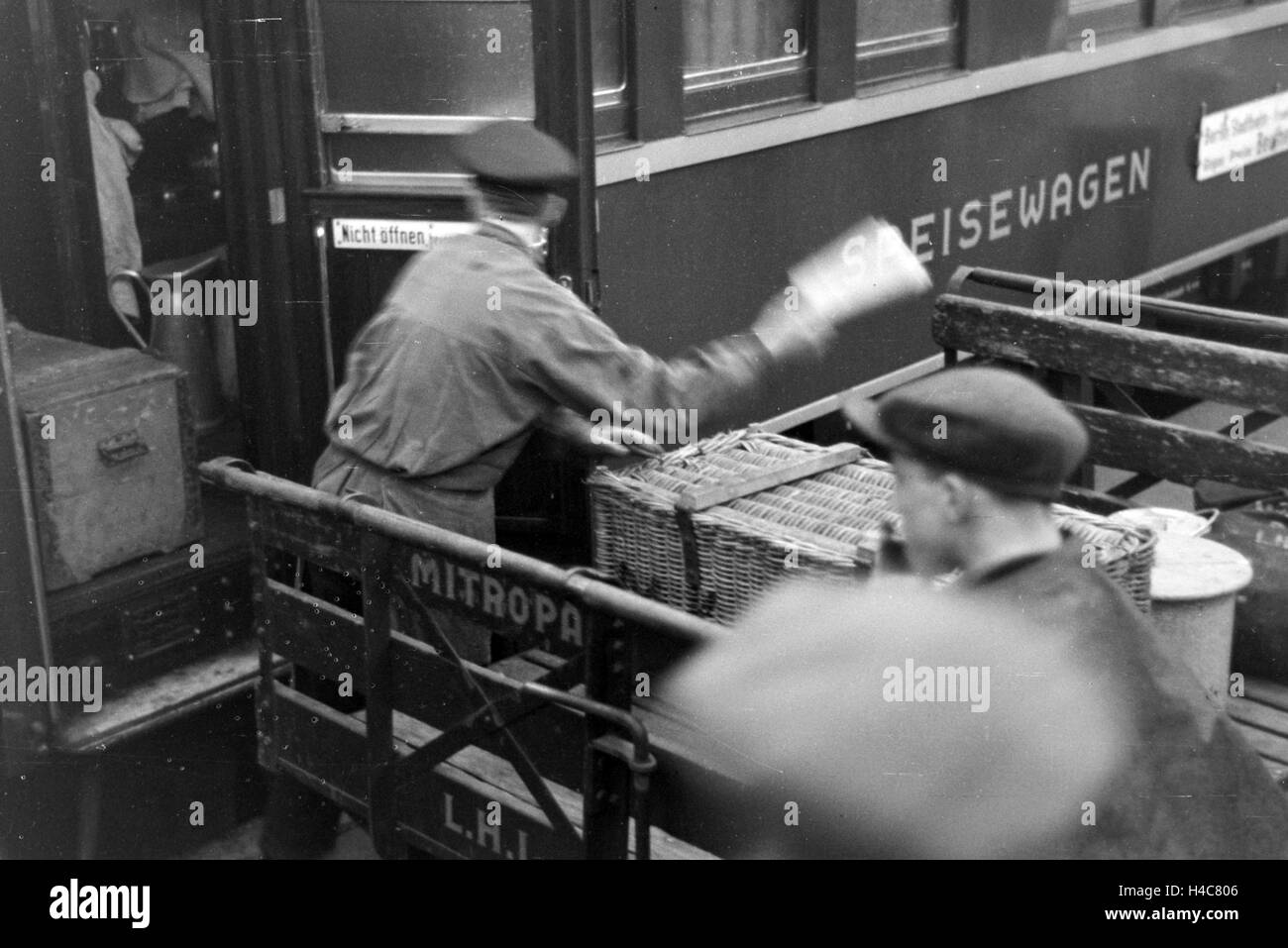 Mitarbeiter der Mitropa bei der Bestückung eines Speisewagens auf dem Bahnhof, Deutschland 1930er Jahre. Staff members charging equipment for the Mitropa dining car, Germany 1930s Stock Photo