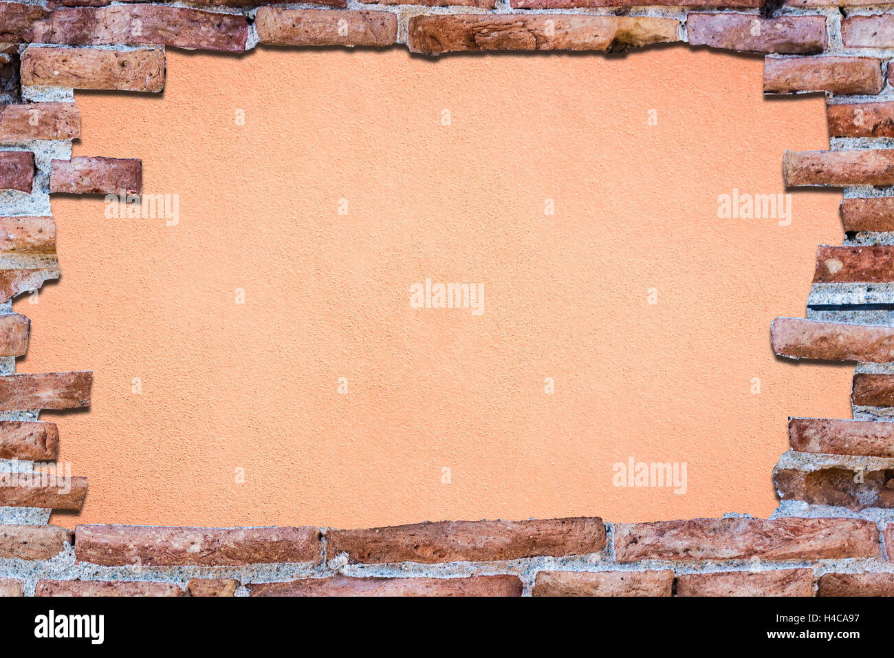 Ancient red brick wall with a hole over a bakground rose. Stock Photo