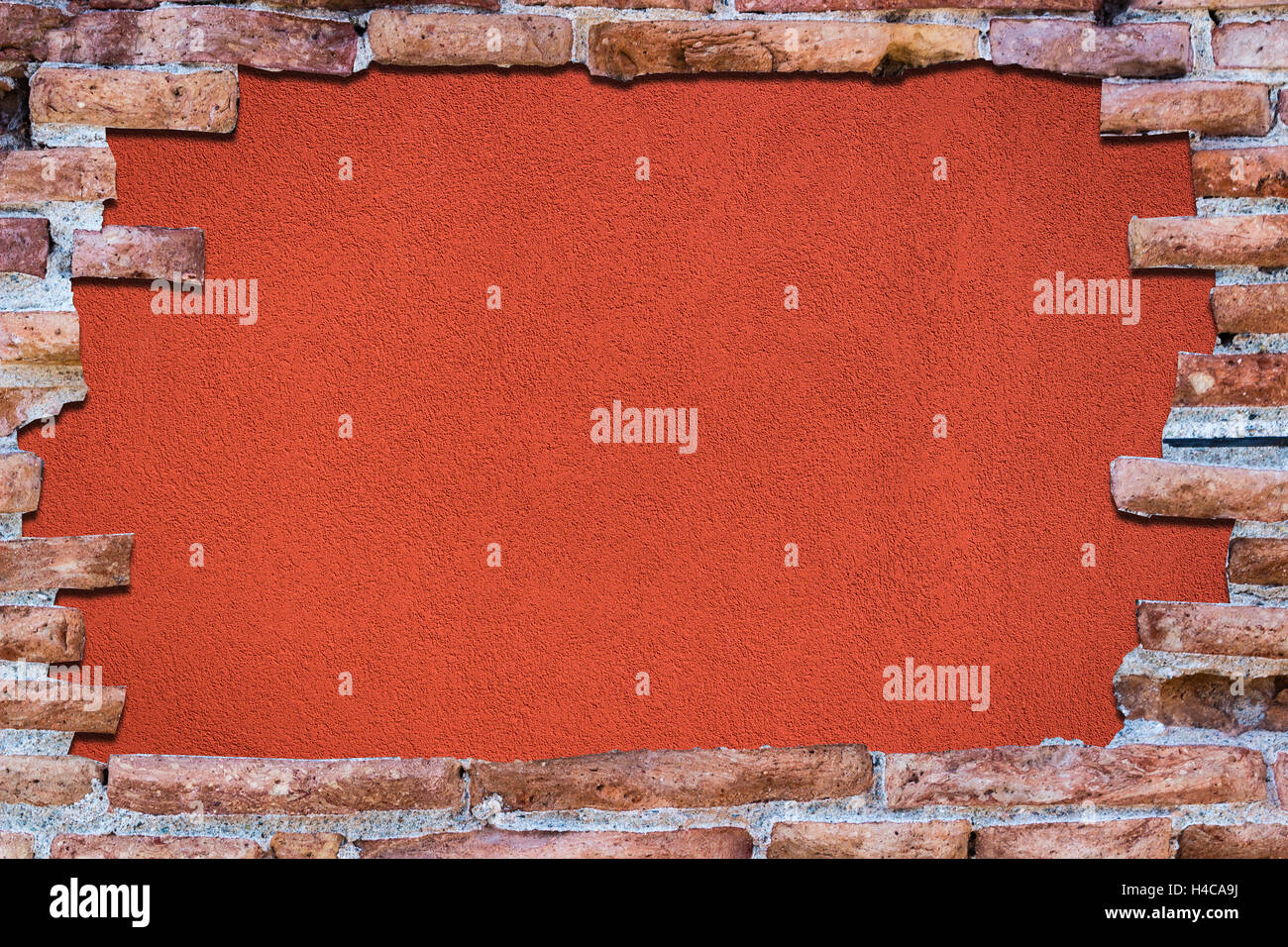 Ancient red brick wall with a hole over a bakground red. Stock Photo