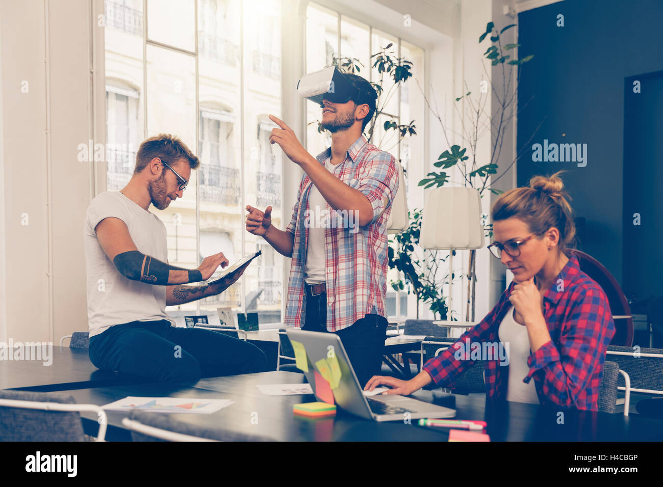 Entrepreneurs testing virtual reality technology with colleague in office. Stock Photo
