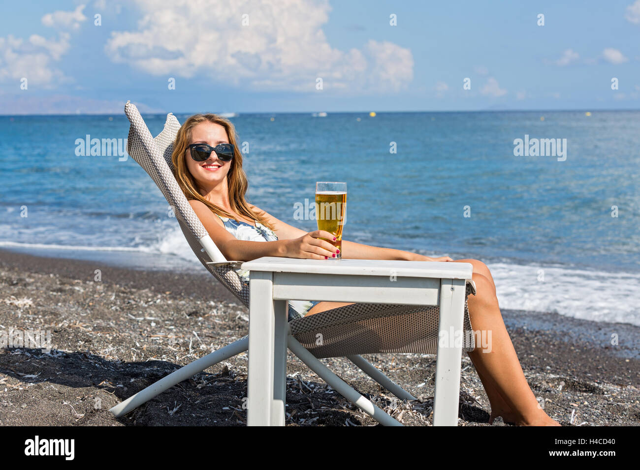Beautiful young woman sunbathing on a lounger on the beach Stock Photo