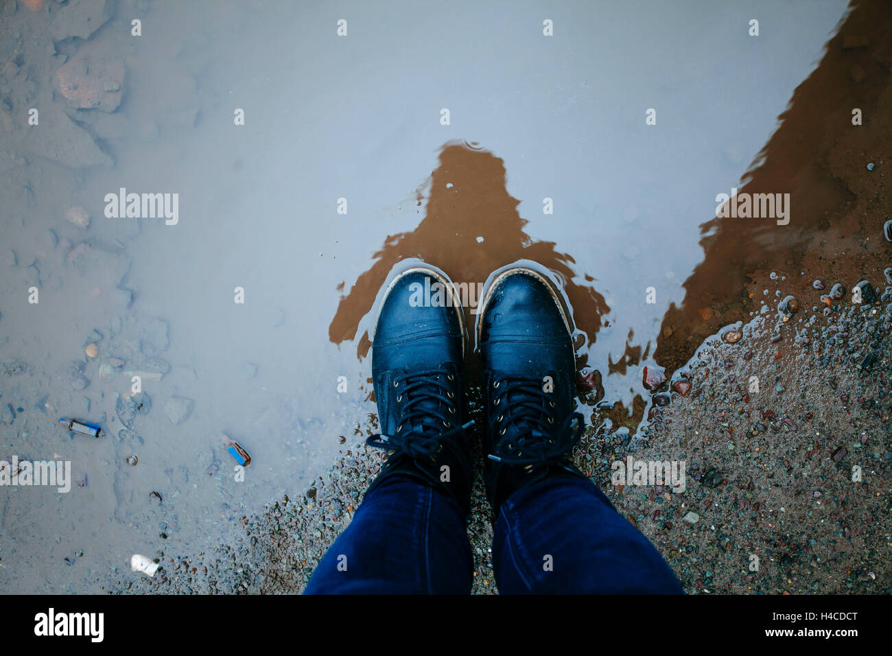 Person, vertical, shoes in puddle, view from above Stock Photo