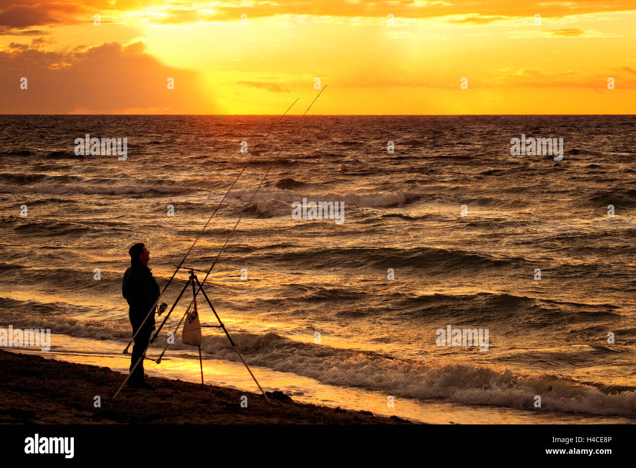 Angler by the sea, vertical, side view, silhouette, sundown Stock Photo