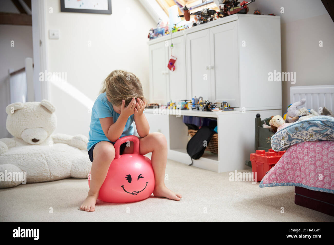 Girl Bounces On Inflatable Ball In Playroom Stock Photo