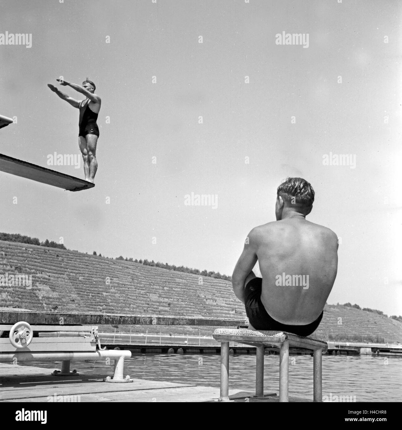 Ein Mann bereitet sich auf seinem Sprung vom Sprungbrett ins Wasser vor, Deutschland 1930er Jahre. A high diver preparing before he jumps, Germany 1930s. Stock Photo