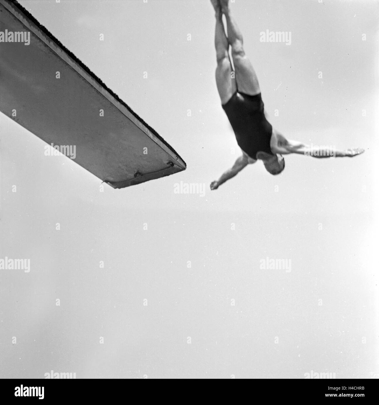 Ein Mann bei einem Sprung vom Sprungbrett ins Wasser, Deutschland 1930er Jahre. A high diver performing, Germany 1930s. Stock Photo