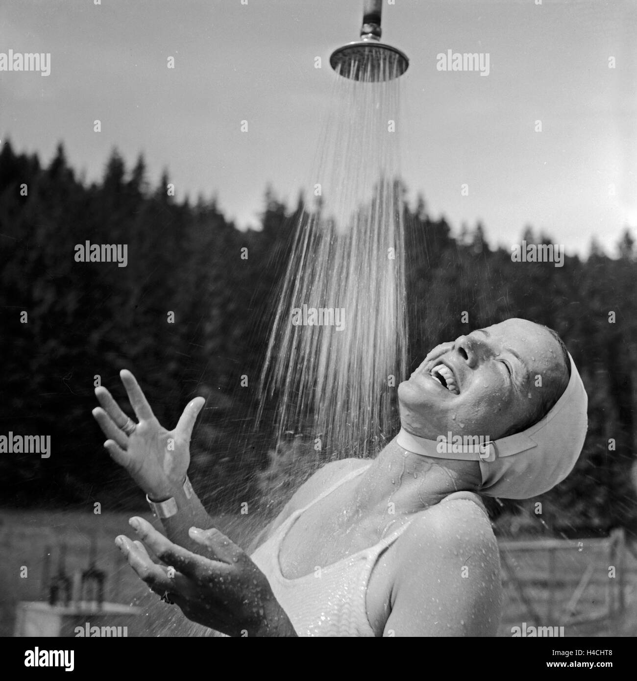 Eine junge Frau nimmt eine kalte Dusche in einem Freibad im Schwarzwald, Deutschland 1930er Jahre. A young woman enjoying a cold shower at an open air pool in Black Forest, Germany 1930s. Stock Photo