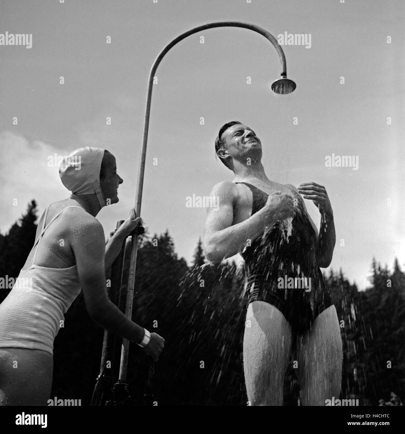 Eine junges Paar nimmt eine kalte Dusche in einem Freibad im Schwarzwald, Deutschland 1930er Jahre. A young couple enjoying a cold shower at an open air pool in Black Forest, Germany 1930s. Stock Photo